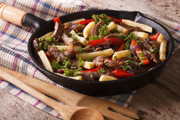 Homemade Peruvian cuisine: lomo saltado in a pan close-up horizontal
