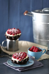 Sweet cakes with raspberries on color wooden background