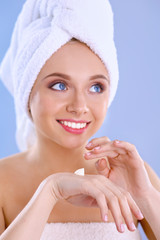 Young woman  putting cream on her hand Isolated on gray background