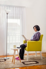  Senior woman reading news paper on sofa at home