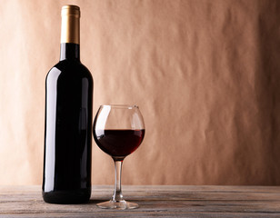 A bottle of red wine and a glass on wooden table