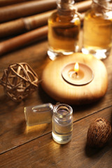 Beautiful decorated composition with candles, pebbles and bamboo on wooden background, close up