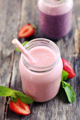 Healthy strawberry yogurt with mint and berries around on wooden background, close up