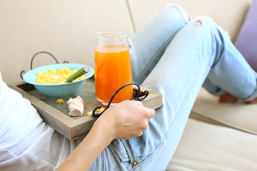 A girl with a tray having lunch on a sofa, close-up