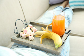 A girl with a tray having lunch on a sofa, close-up