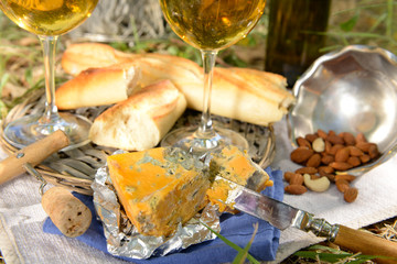 Beautiful composition of wine, cheese, almonds and baguette outdoors, close up