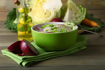 Savoy cabbage and onion salad served in bowl on wooden table