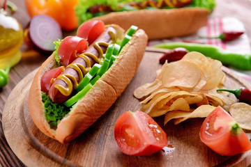 Hot dog and vegetables on wooden cutting board