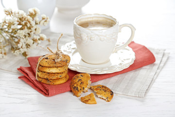 Cup of coffee and pile of tasty cookies with chocolate crumbs on white wooden table