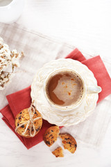 Cup of coffee and pile of tasty cookies with chocolate crumbs on white wooden table