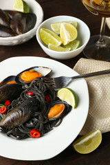 Cooked pasta, mussel and lime on brown wooden background