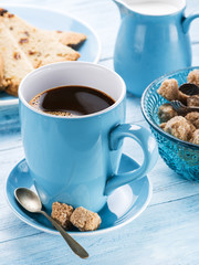 Cup of coffee, milk jug, cane sugar cubes and fruit-cake.