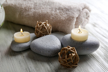 Composition of flowers, candles and stones on white wooden background, in spa salon