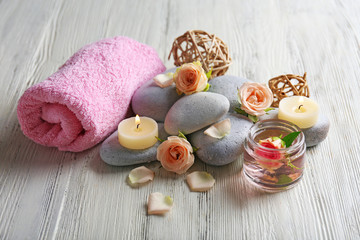 Composition of flowers, candles and stones on white wooden background, in spa salon