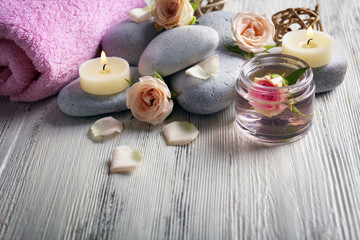 Obraz na płótnie Canvas Composition of flowers, candles and stones on white wooden background, in spa salon