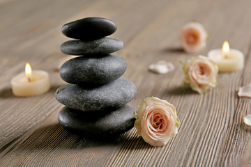 Fototapeta na wymiar Composition of flowers, candles and stones on brown wooden background, in spa salon