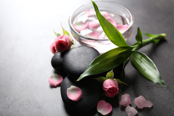 Spa composition of stones, flowers and petals, on grey background