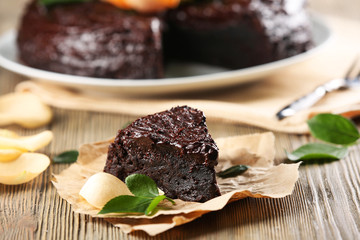 Piece of chocolate cake decorated with flowers on brown wooden table