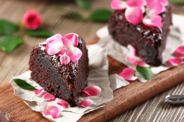 Piece of chocolate cake decorated with flowers on brown wooden table