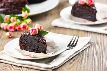 Piece of chocolate cake decorated with flowers on brown wooden table