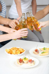 Friends hands with bottles of beer and snacks , close up