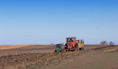 Two tractors working on fertilizing field