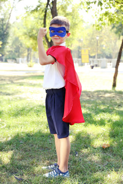 Boy dressed as superhero with boxing gloves plays at the park