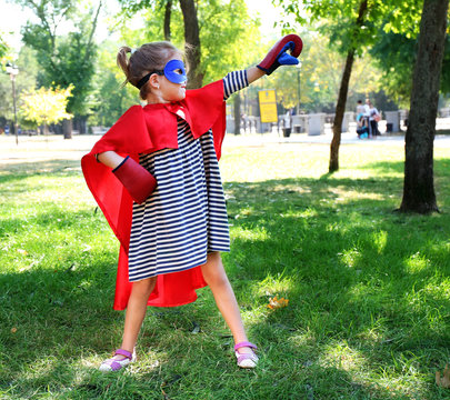 Little girl dressed as superhero in boxing gloves at the park