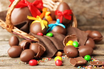 Chocolate Easter eggs in basket on wooden background