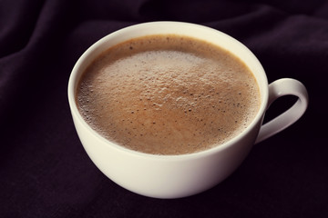 Cup of coffee and sugar on black tablecloth closeup