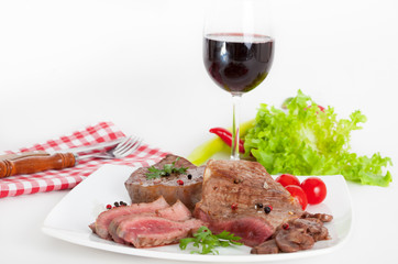 Beef steak on white plate with glass of red wine