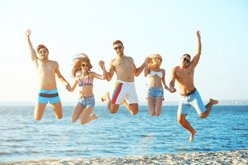 Happy friends jumping at the beach, outdoors