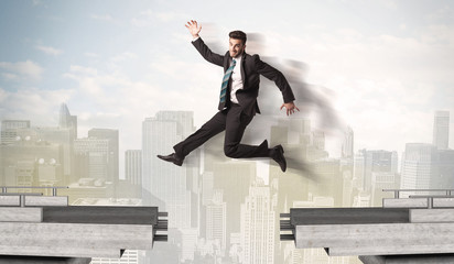 Energetic business man jumping over a bridge with gap