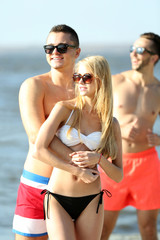 Happy couple and their playful friends relaxing at the beach, outdoors