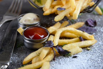 French fries with sauce and tableware on table, close-up