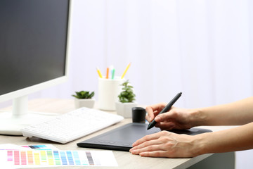 Fototapeta premium Female hand drawing on the graphic tablet in the office, close-up