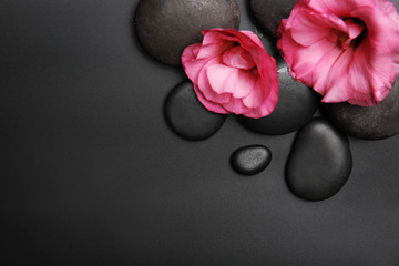 Spa stones and flowers on black background