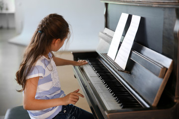 Cute little girl studding to play piano