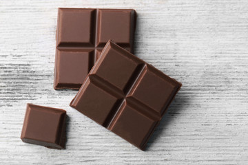 Milk chocolate pieces on color wooden background