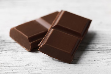 Black chocolate pieces on color wooden background