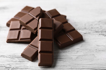 Black chocolate pieces on color wooden background