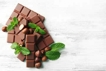 Chocolate pieces with nuts on color wooden background