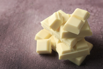White chocolate pieces on color wooden background