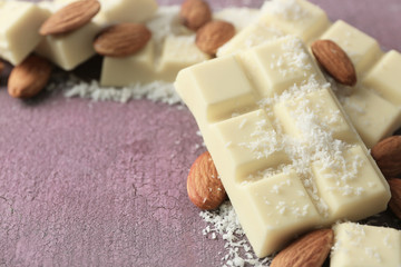 Fototapeta na wymiar White chocolate pieces with nuts on color wooden background
