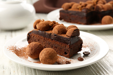 Chocolate balls and a piece of cake with walnut on the table, close-up