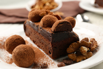 Chocolate balls and a piece of cake with walnut on the table, close-up