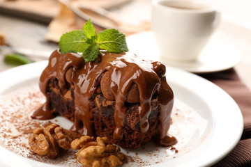A piece of chocolate cake with walnut and mint on the table, close-up