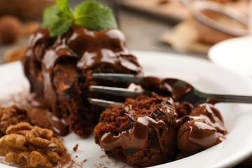 A piece of chocolate cake with walnut and mint on the table, close-up