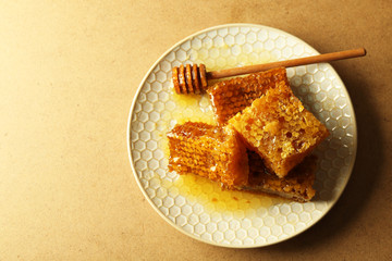 Honeycombs and wooden dipper on plate on wooden background