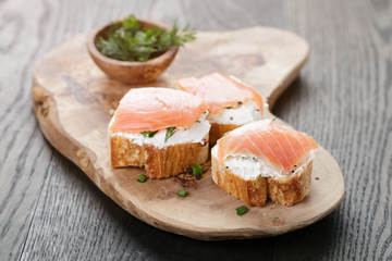 baguette slices with soft cheese and salmon on wood table